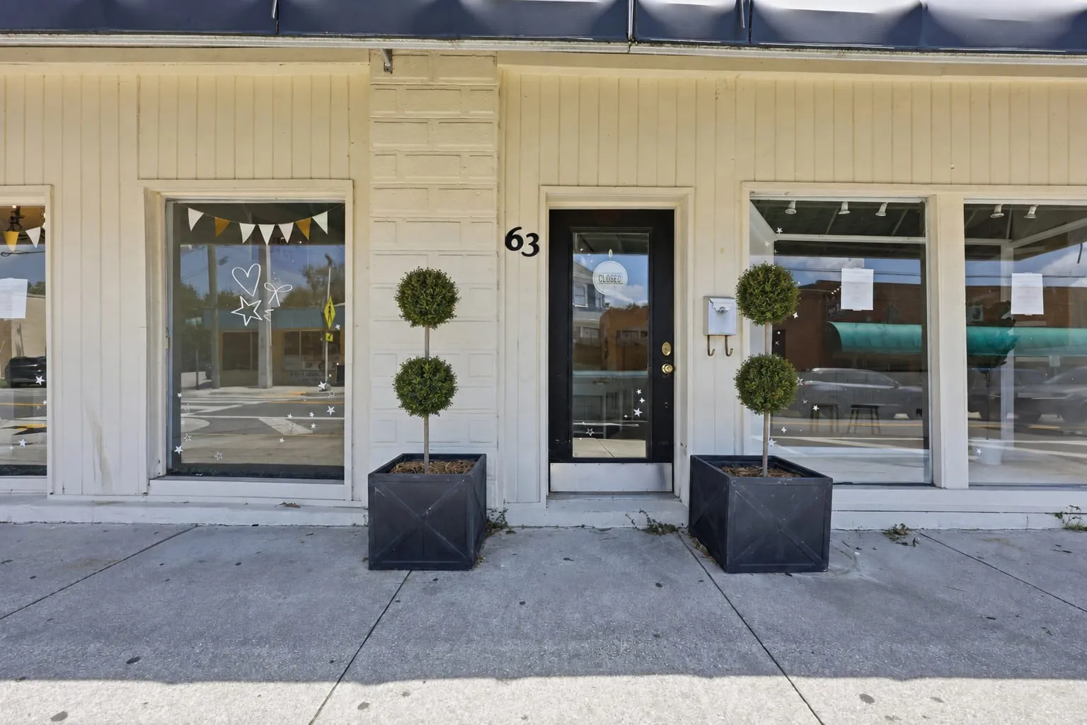 Entry at 63 San Marco Avenue with the street number, display windows and planted topiaries